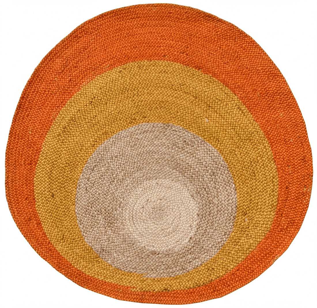 a circular rug with a vibrant, multicolored design. The rug has concentric circles of different colors, including shades of orange, yellow, and gray, creating a visually striking and eye-catching pattern.